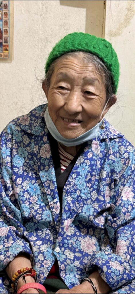 Older woman wearing a green knitted cap and a blue floral shawl